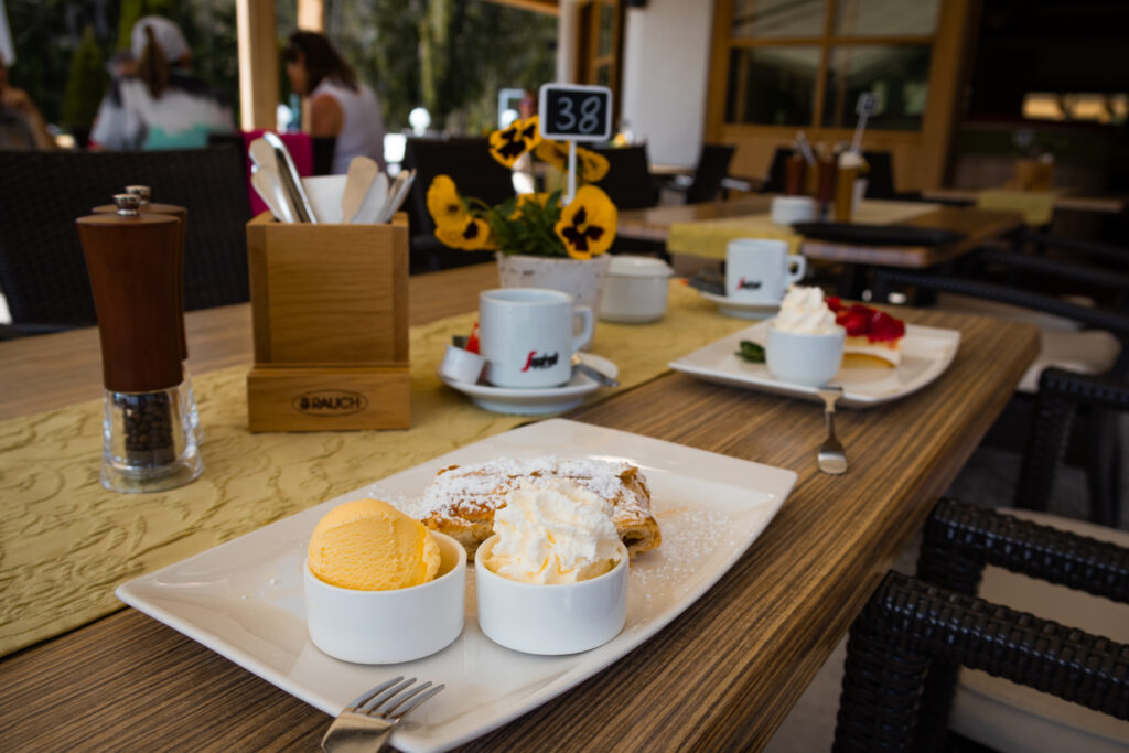 Apfelstrudel mit Eis und Sahne auf der Sonnenterrasse des Clubrestaurants des Kaiserwinkl Golf Kössen - Lärchnehof.